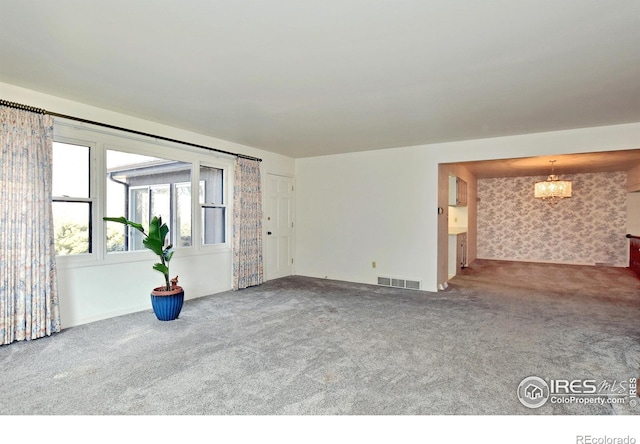 unfurnished living room with carpet flooring and a chandelier