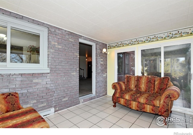 interior space with light tile patterned floors, brick wall, and a baseboard radiator