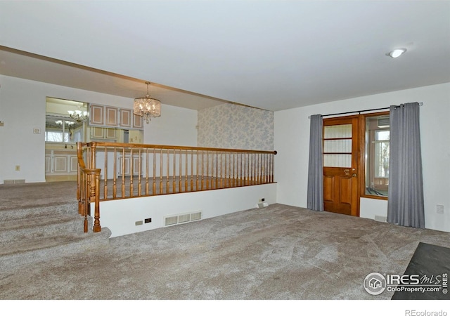 spare room featuring carpet flooring and an inviting chandelier