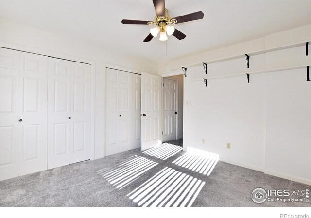 unfurnished bedroom with multiple closets, ceiling fan, and carpet