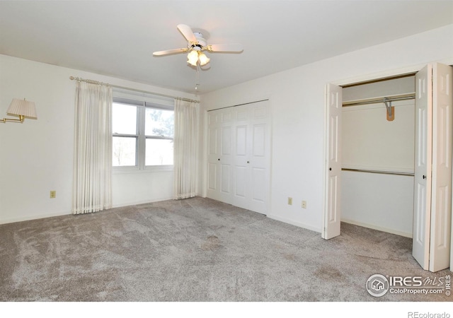 unfurnished bedroom with ceiling fan, light colored carpet, and two closets