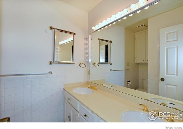 bathroom featuring vanity, toilet, and tile walls