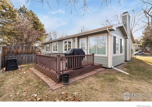 back of property featuring a wooden deck and a lawn