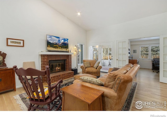 living room featuring a fireplace, light hardwood / wood-style floors, and vaulted ceiling