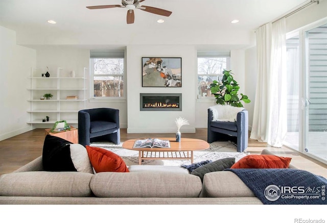 living room with light hardwood / wood-style flooring, ceiling fan, and a healthy amount of sunlight