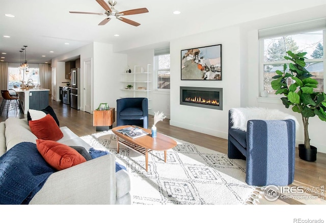 living room featuring hardwood / wood-style flooring, ceiling fan, and sink