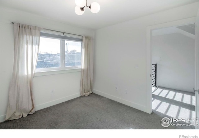 carpeted empty room with a chandelier