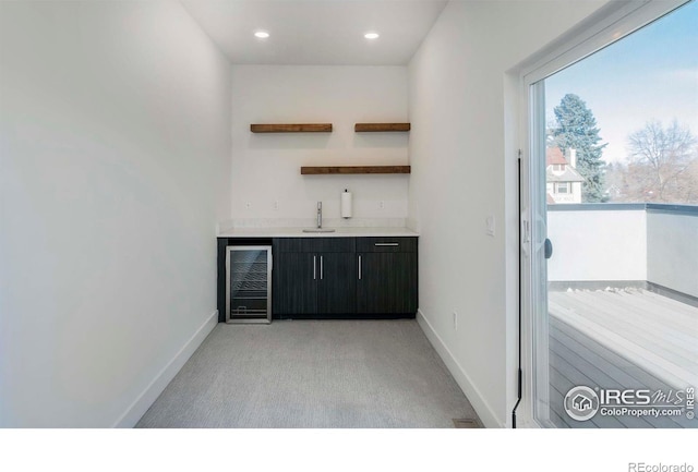 bar featuring light colored carpet, dark brown cabinetry, sink, and beverage cooler