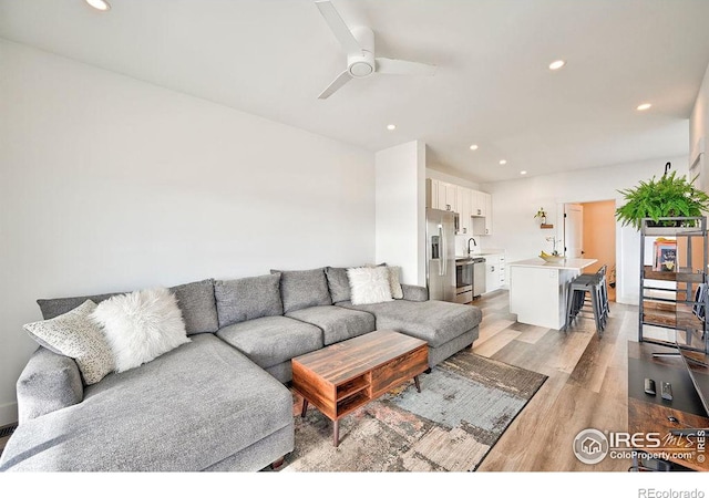 living room with ceiling fan, sink, and light hardwood / wood-style flooring