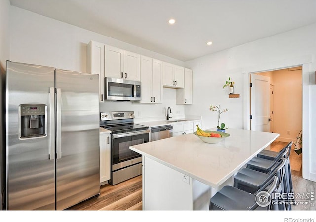 kitchen featuring white cabinetry, a kitchen island, light wood-type flooring, and appliances with stainless steel finishes