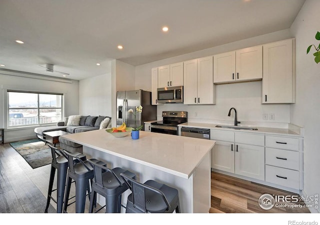 kitchen featuring a breakfast bar, white cabinetry, light hardwood / wood-style flooring, and appliances with stainless steel finishes