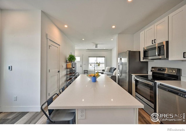 kitchen featuring white cabinetry, a center island, stainless steel appliances, and light hardwood / wood-style floors