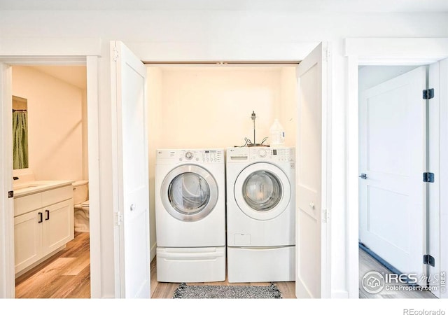 laundry area with washing machine and dryer and light wood-type flooring