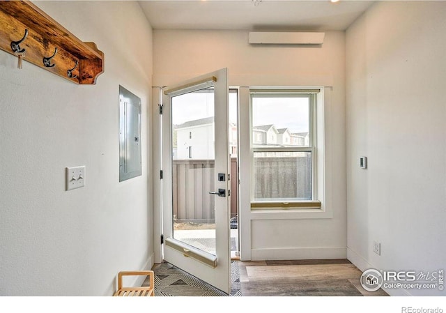 doorway to outside with light hardwood / wood-style flooring, electric panel, and a wall mounted AC