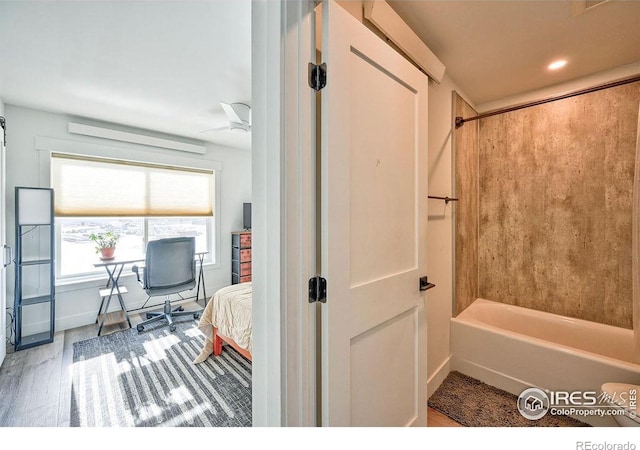 bathroom with hardwood / wood-style floors, ceiling fan, and shower / tub combination