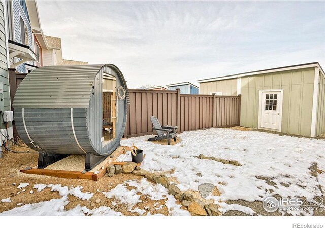 snowy yard featuring a storage shed