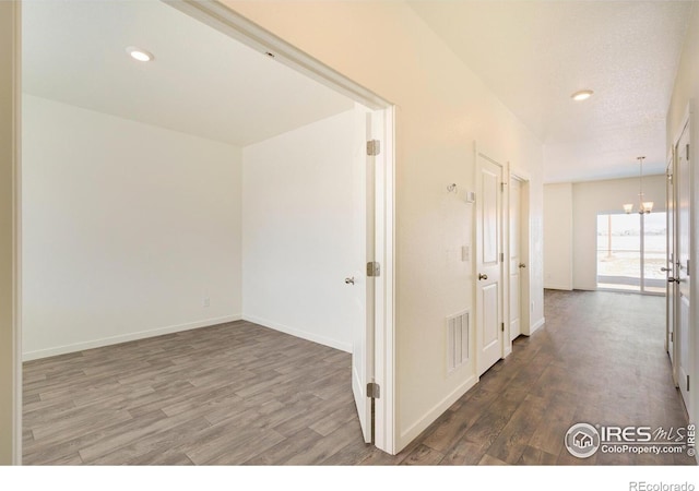 corridor featuring a notable chandelier and dark wood-type flooring