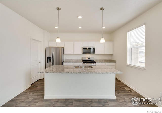 kitchen with white cabinetry, hanging light fixtures, stainless steel appliances, and a center island with sink