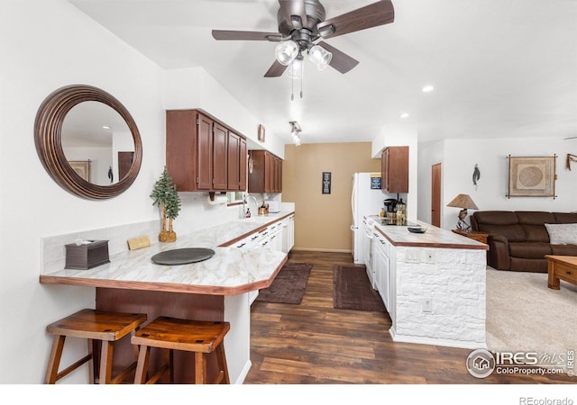 kitchen with dark hardwood / wood-style flooring, a kitchen bar, kitchen peninsula, and sink