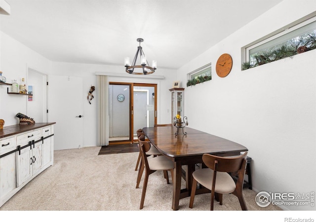 dining room featuring light colored carpet and a notable chandelier