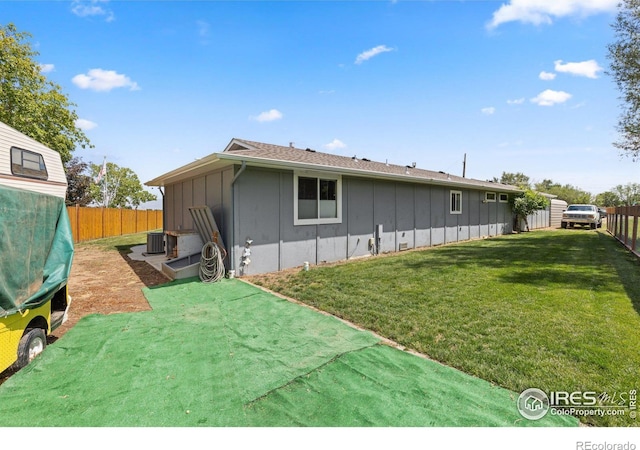 rear view of property featuring a lawn and cooling unit