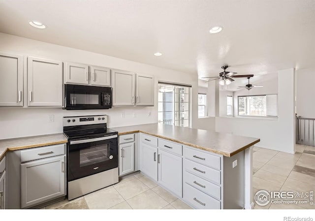 kitchen featuring a peninsula, stainless steel electric range oven, black microwave, and light countertops