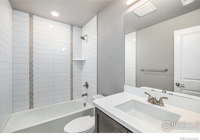 full bathroom featuring vanity, tiled shower / bath combo, and toilet