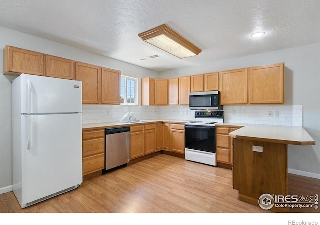 kitchen featuring light hardwood / wood-style floors, kitchen peninsula, a textured ceiling, and appliances with stainless steel finishes