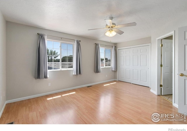 unfurnished bedroom featuring ceiling fan, a closet, a textured ceiling, and light wood-type flooring