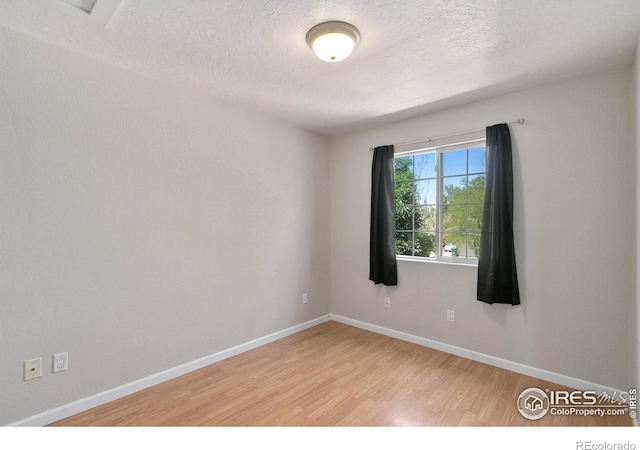 spare room with hardwood / wood-style floors and a textured ceiling