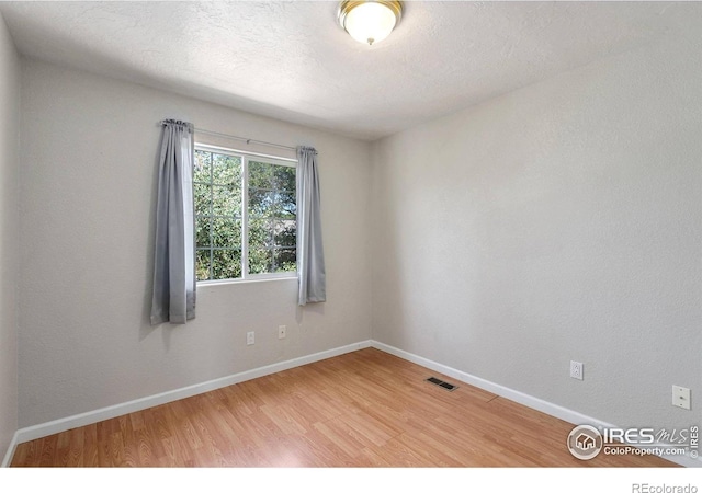 empty room featuring wood-type flooring and a textured ceiling