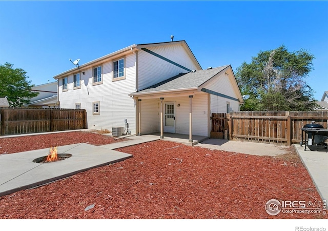 rear view of property featuring a fire pit, central AC unit, and a patio