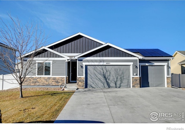 craftsman inspired home with a front yard, solar panels, and a garage