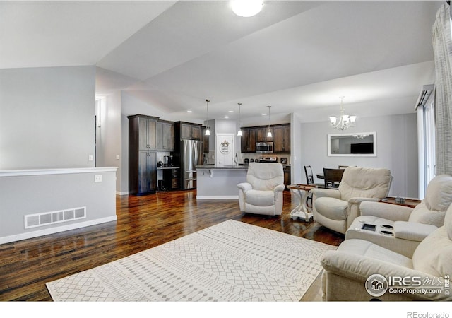 living room with dark wood-type flooring, a chandelier, and vaulted ceiling