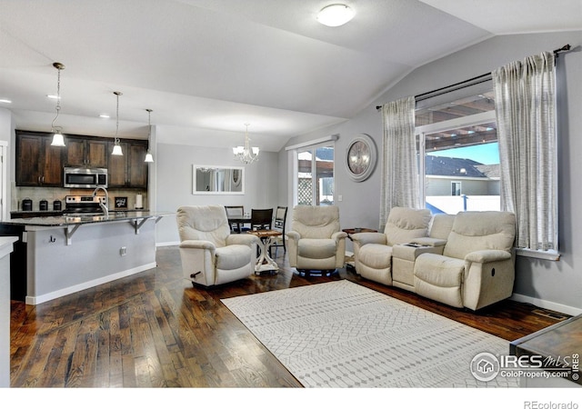 living room featuring lofted ceiling, dark hardwood / wood-style flooring, a chandelier, and sink