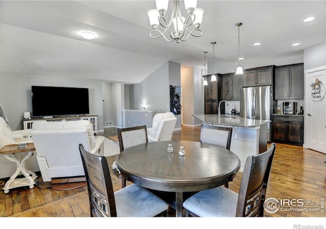 dining area with hardwood / wood-style flooring, an inviting chandelier, and sink