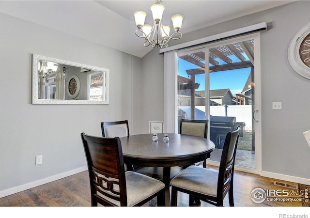 dining area with dark hardwood / wood-style floors and a chandelier