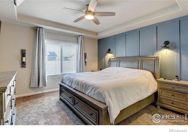 carpeted bedroom with ceiling fan and a tray ceiling