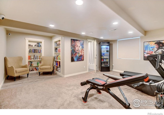 exercise room with built in shelves and light carpet