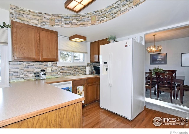 kitchen featuring sink, a chandelier, pendant lighting, white appliances, and light hardwood / wood-style floors