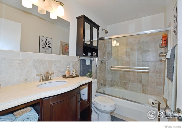 full bathroom featuring decorative backsplash, vanity, toilet, and bath / shower combo with glass door