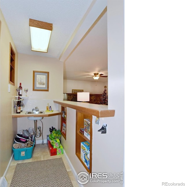 hall with light tile patterned flooring, sink, and a textured ceiling