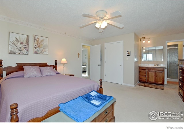 carpeted bedroom featuring ensuite bath, ceiling fan, and a textured ceiling