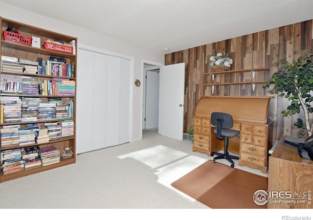 office featuring a textured ceiling, carpet floors, and wood walls