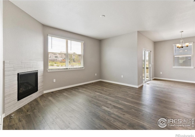 unfurnished living room featuring a chandelier and dark hardwood / wood-style floors