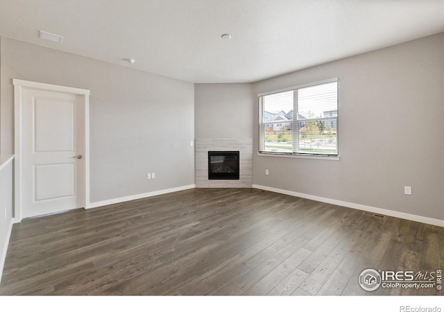 unfurnished living room featuring dark hardwood / wood-style flooring and a brick fireplace