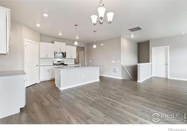 kitchen with pendant lighting, a kitchen island with sink, dark wood-type flooring, white cabinets, and stainless steel appliances