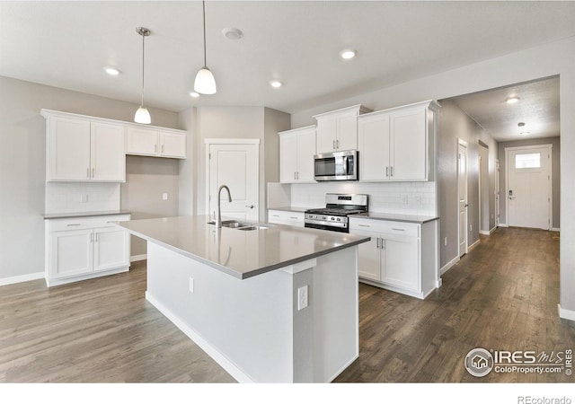 kitchen featuring dark wood-type flooring, a center island with sink, white cabinets, sink, and stainless steel appliances