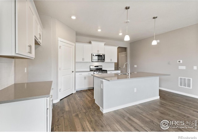 kitchen featuring white cabinetry, stainless steel appliances, tasteful backsplash, dark hardwood / wood-style floors, and a kitchen island with sink