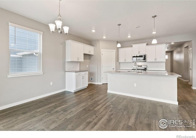 kitchen featuring dark hardwood / wood-style flooring, stainless steel appliances, a kitchen island with sink, white cabinetry, and hanging light fixtures